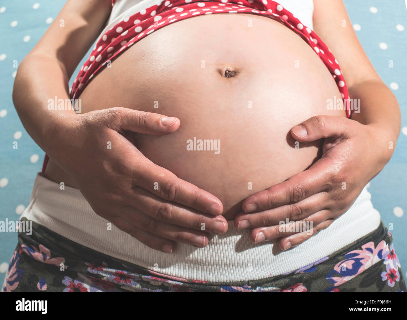 Donna incinta mostra il suo ventre. Sfondo blu Foto Stock