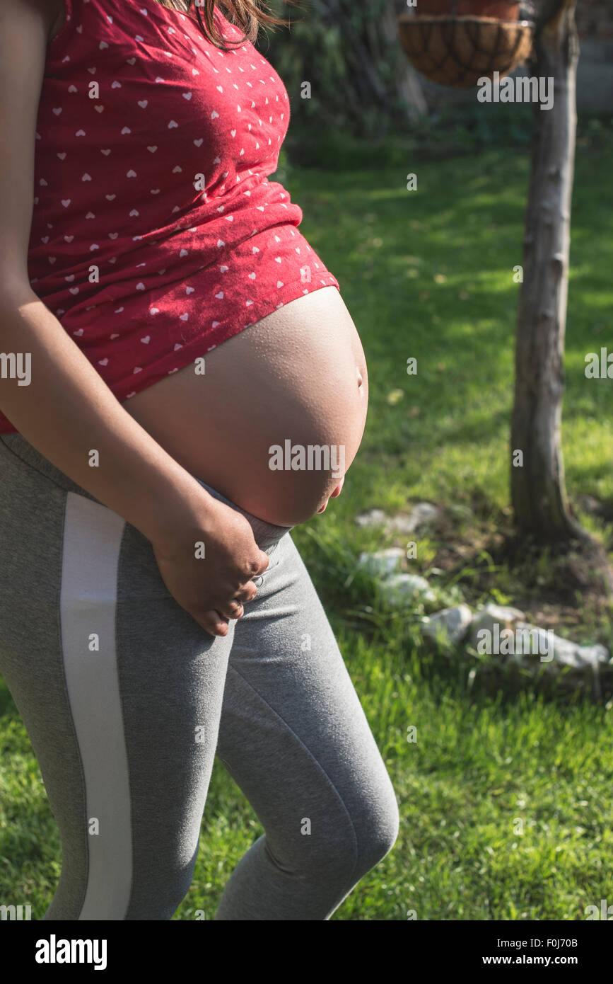 Donna incinta mostra il suo ventre. In natura. Verde prato Foto Stock