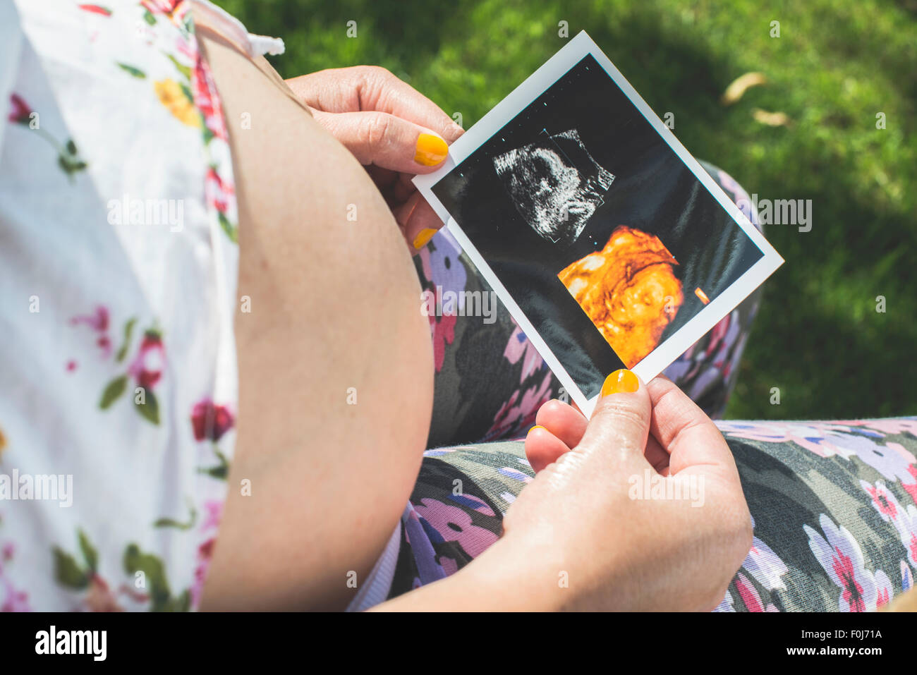 Donne in stato di gravidanza fermo immagine del grembo. La luce diurna in giardino Foto Stock