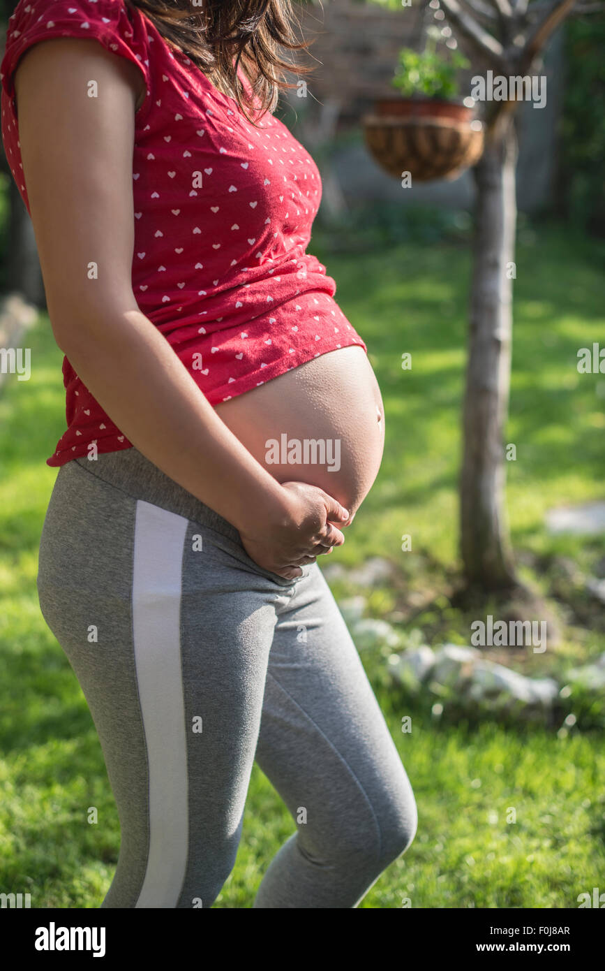 Donna incinta mostra il suo ventre. In natura. Verde prato Foto Stock
