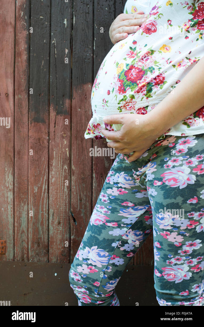 Donne in stato di gravidanza nella parte anteriore del vecchio rosso parete in legno. Foto Stock