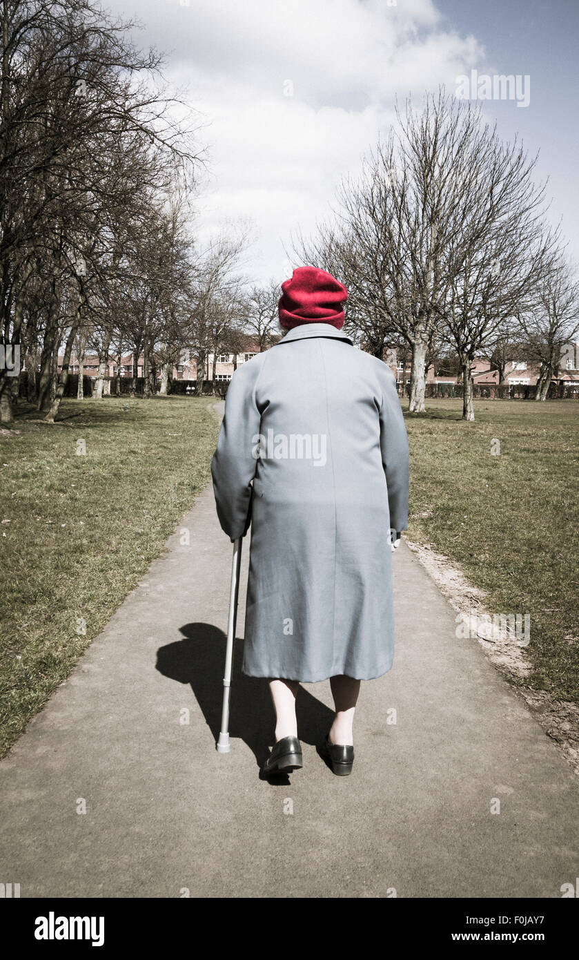 Novantenne lady camminare con il bastone nel parco pubblico. In Inghilterra. Regno Unito Foto Stock