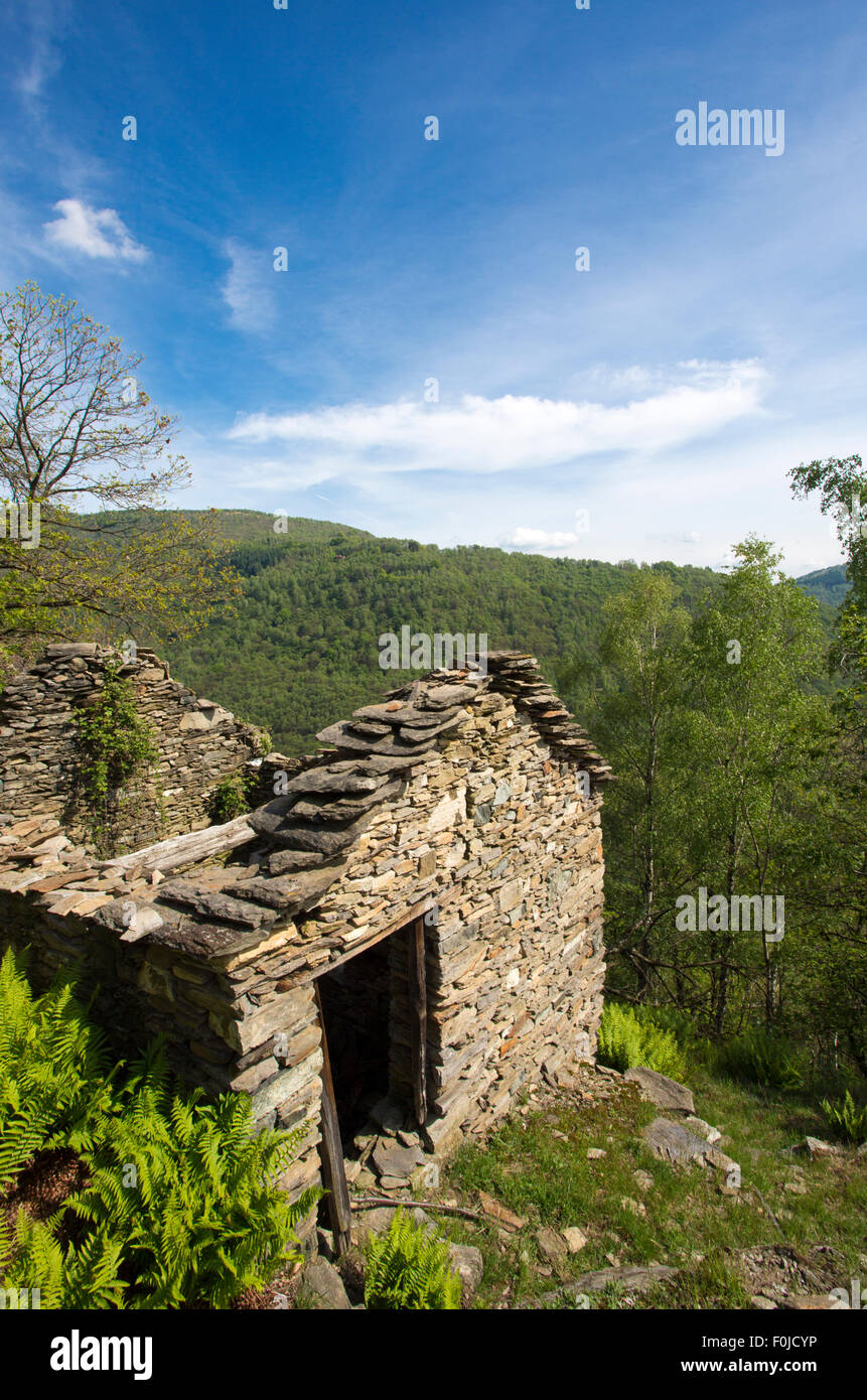 Abbandonate le antiche pietre house con il blu del cielo e le foreste in background nel nord Italia, Scareno, vicino a Verbania. Foto Stock