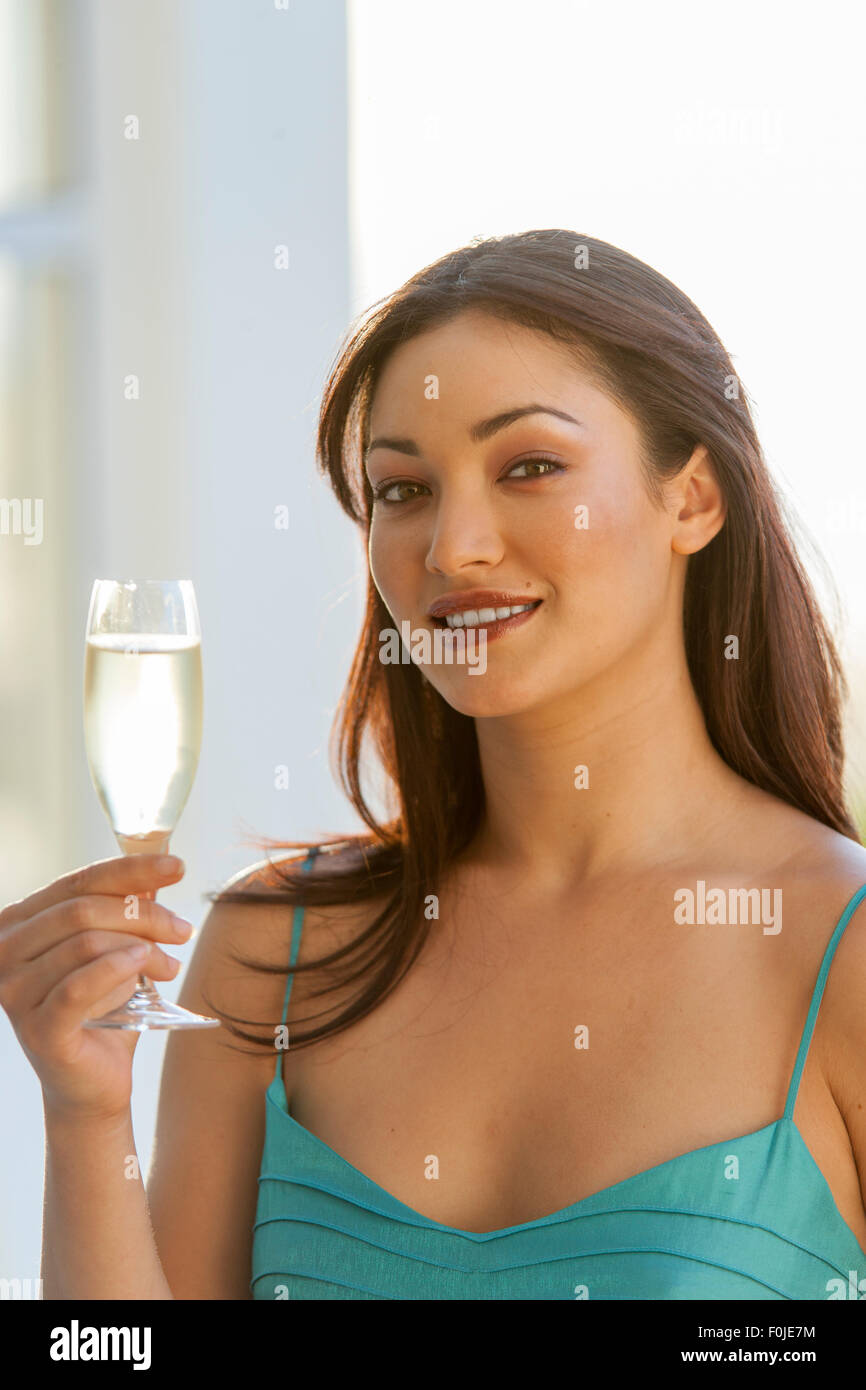 Giovane donna attraente in abito da sera con in mano un bicchiere di champagne Foto Stock