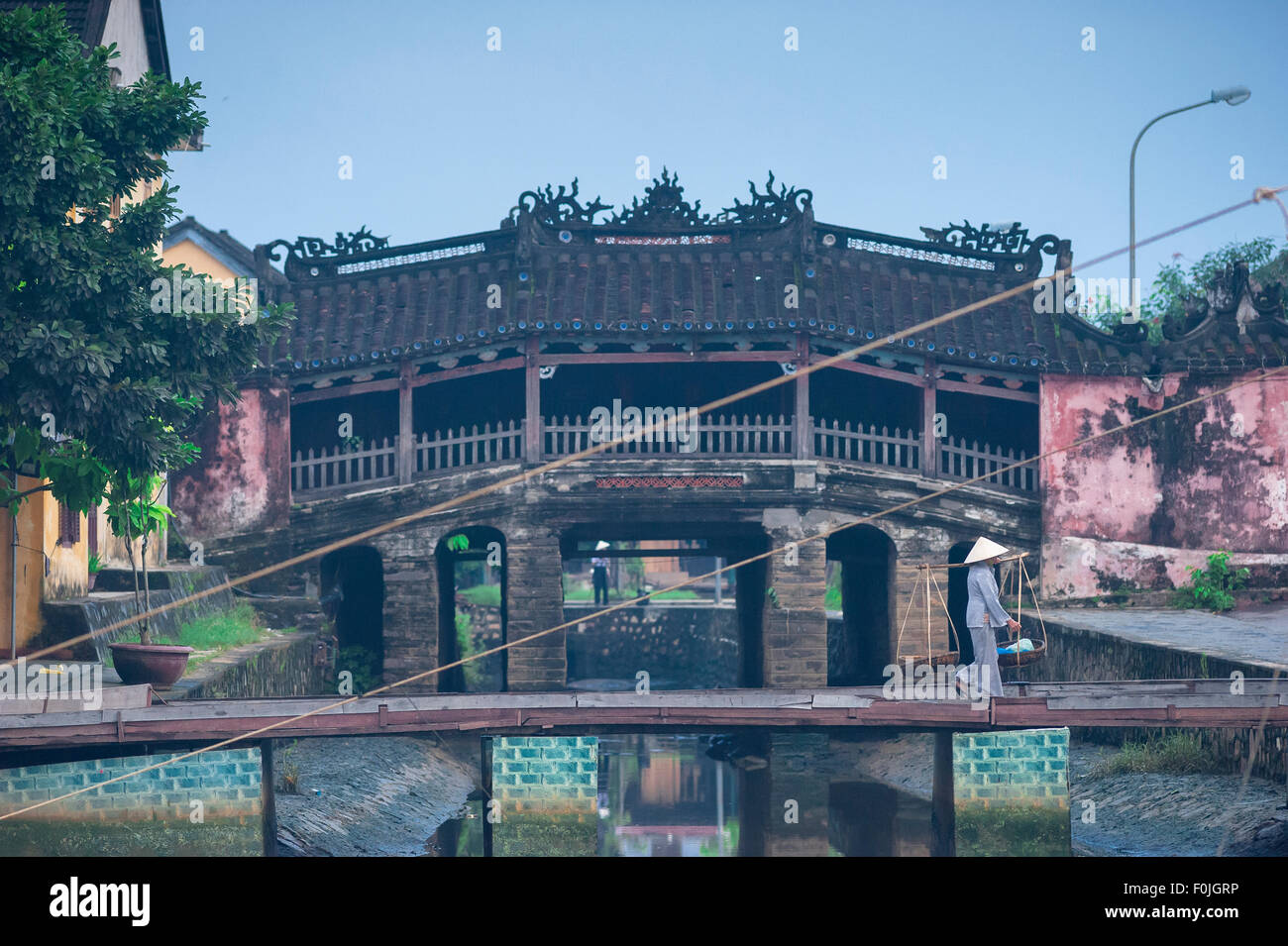 Ponte giapponese Hoi An, vista all'alba di una donna che passa il ponte giapponese sulla strada per il mercato mattutino, Vietnam Foto Stock