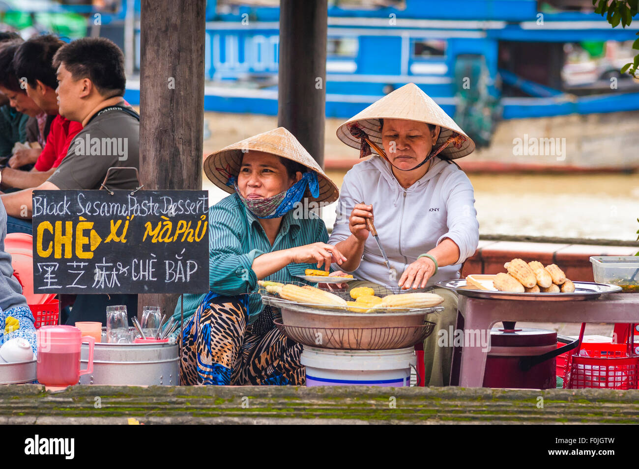 Cibo di strada Hoi An, vista di due donne vietnamite che grigliano mais dolce lungo il lungomare di Hoi An, Vietnam centrale. Foto Stock
