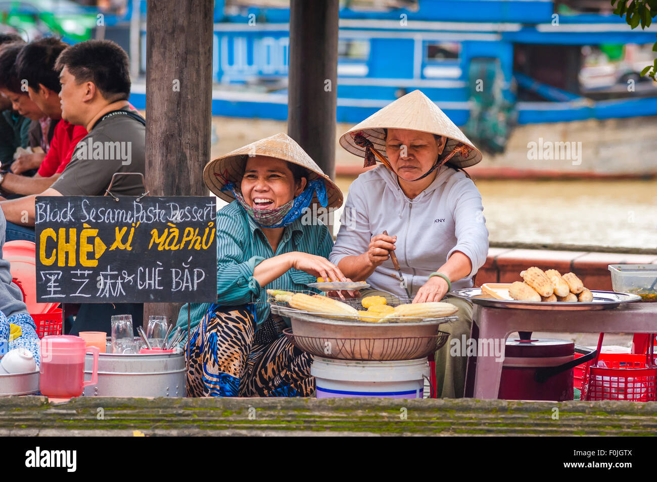 Cibo di strada vietnamita, veduta delle venditrici di cibo che grigliano mais dolce lungo il lungomare di Hoi An, Vietnam centrale. Foto Stock