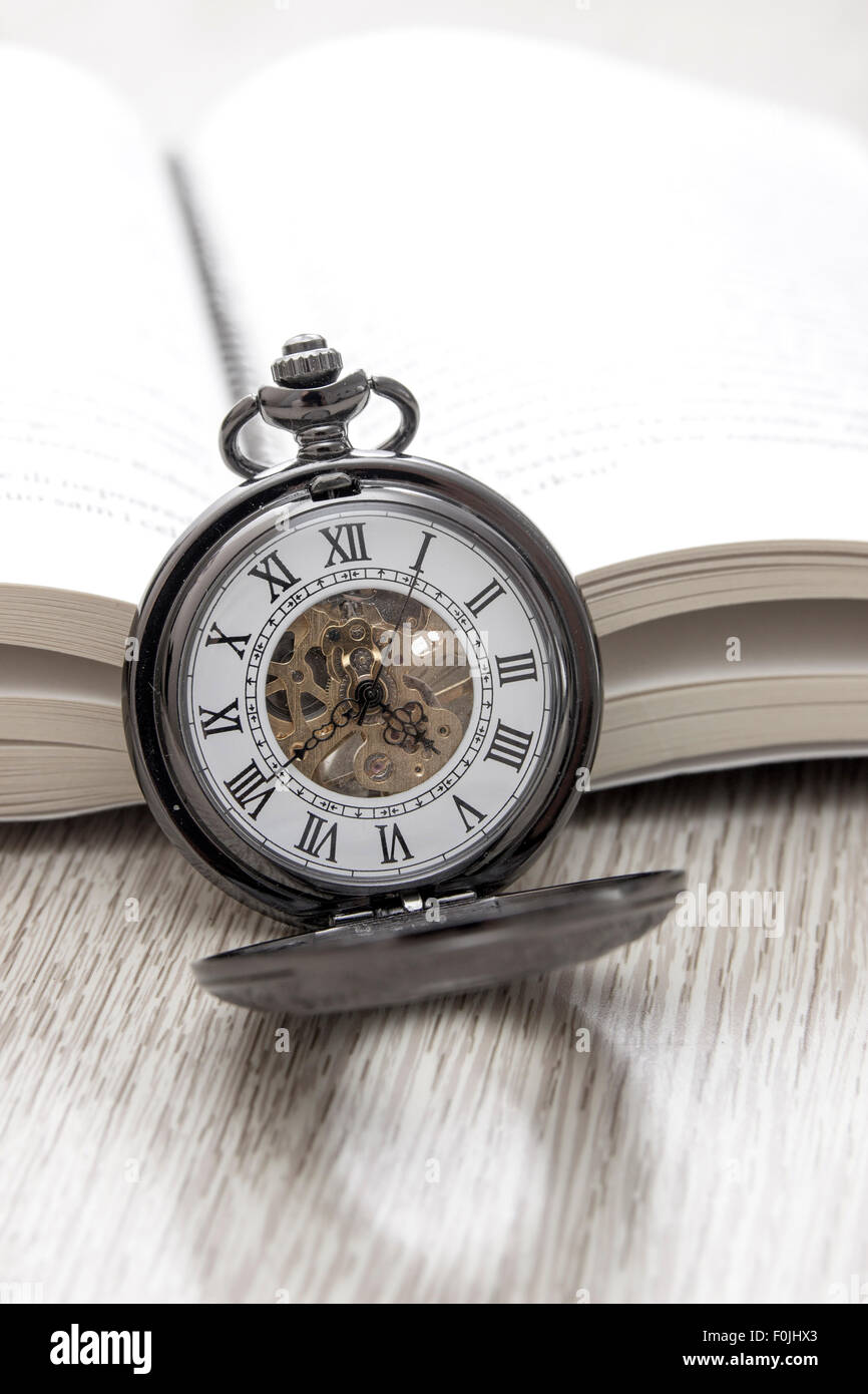 Il vecchio orologio da tasca e un libro sul tavolo, close up Foto Stock