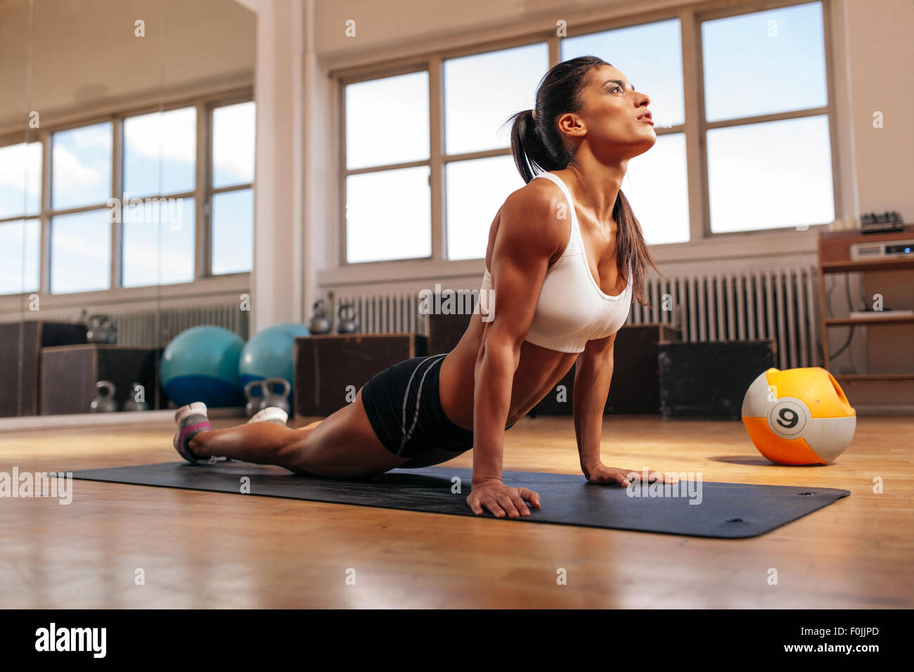 Donna facendo core tratto sul tappetino fitness. Muscolare di giovane donna facendo stretching esercizio in palestra. Foto Stock