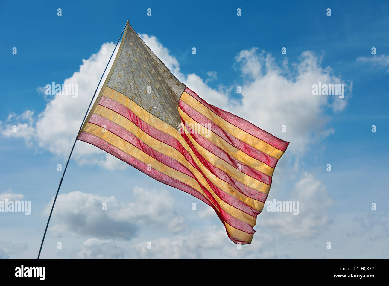 Sbiadita bandiera americana battenti contro un cielo blu Foto Stock