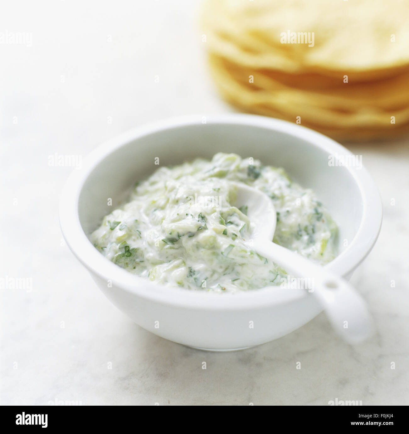 Salsa Raita servita in un piccolo recipiente in plastica con il cucchiaio, close up Foto Stock