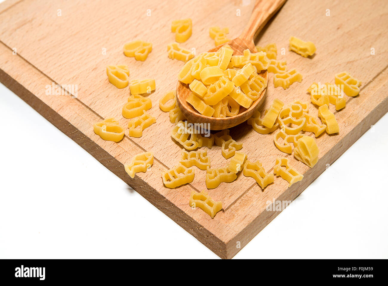 La pasta in forma di animali e un cucchiaio di legno su sfondo bianco Foto Stock