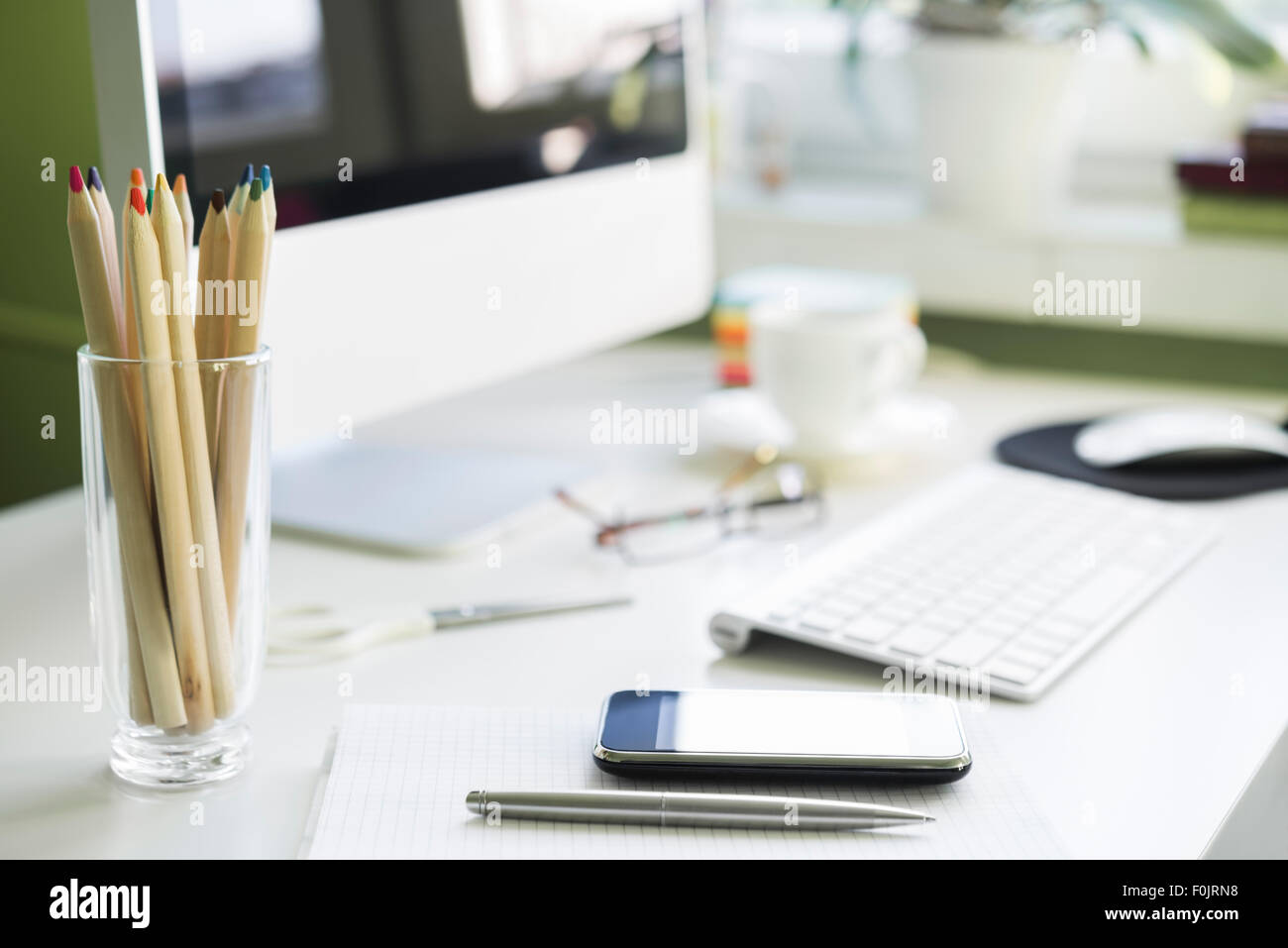 Postazione di lavoro con computer sul tavolo bianco. Focus sullo smartphone Foto Stock