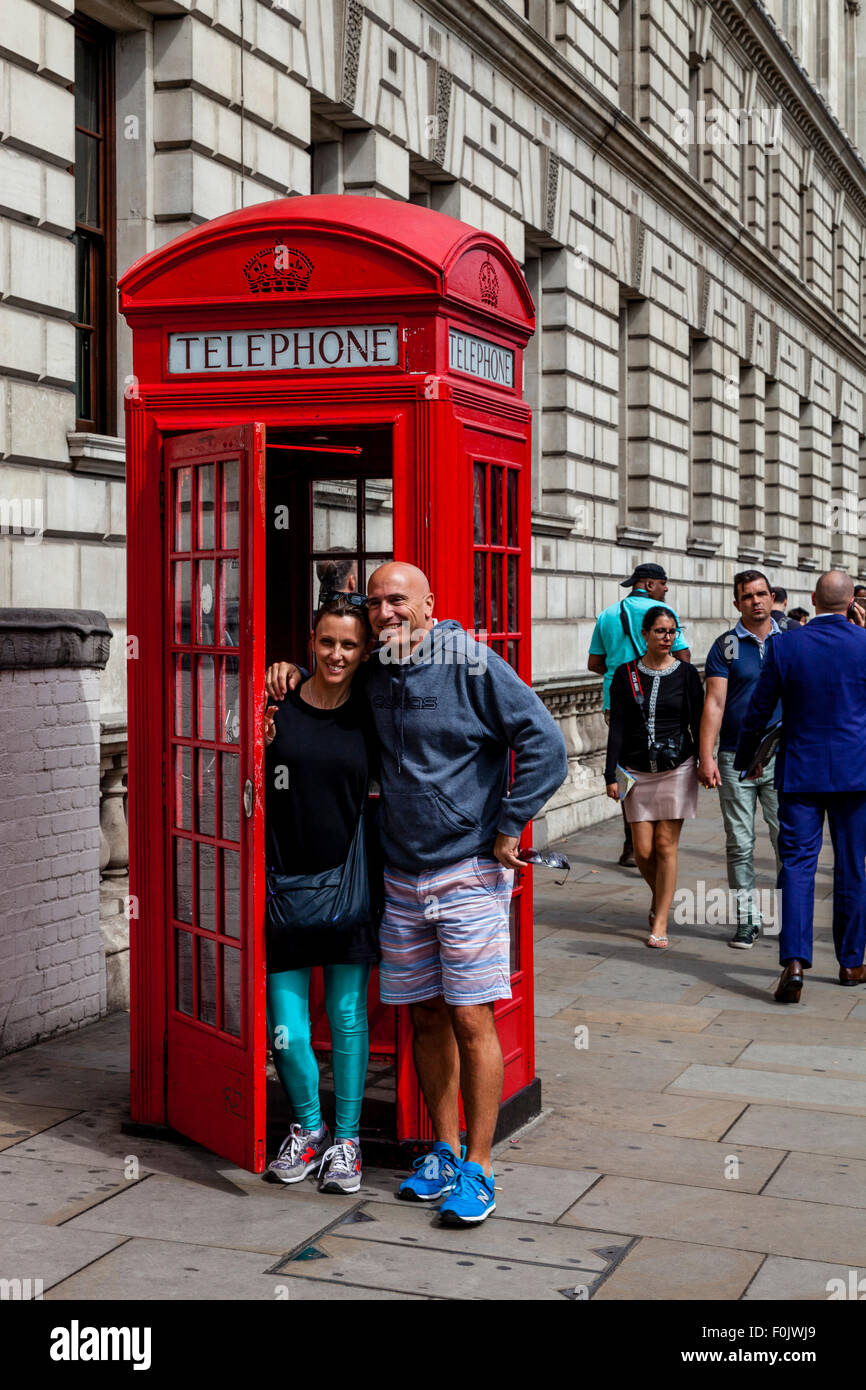 I turisti pongono per fotografie di un tradizionale telefono rosso scatola, Londra, Inghilterra Foto Stock