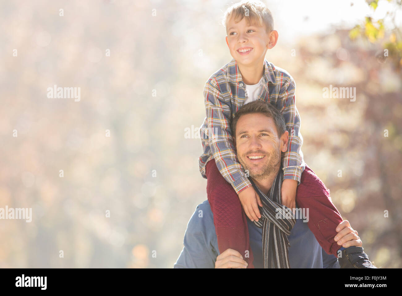 Sorridente padre figlio che porta sulle spalle all'aperto Foto Stock