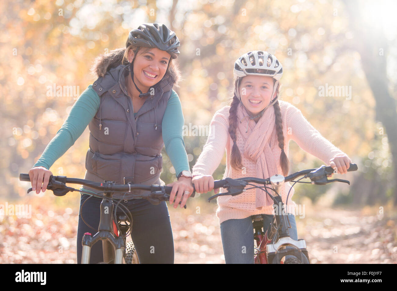 Ritratto di sorridente madre e figlia in mountain bike nei boschi Foto Stock