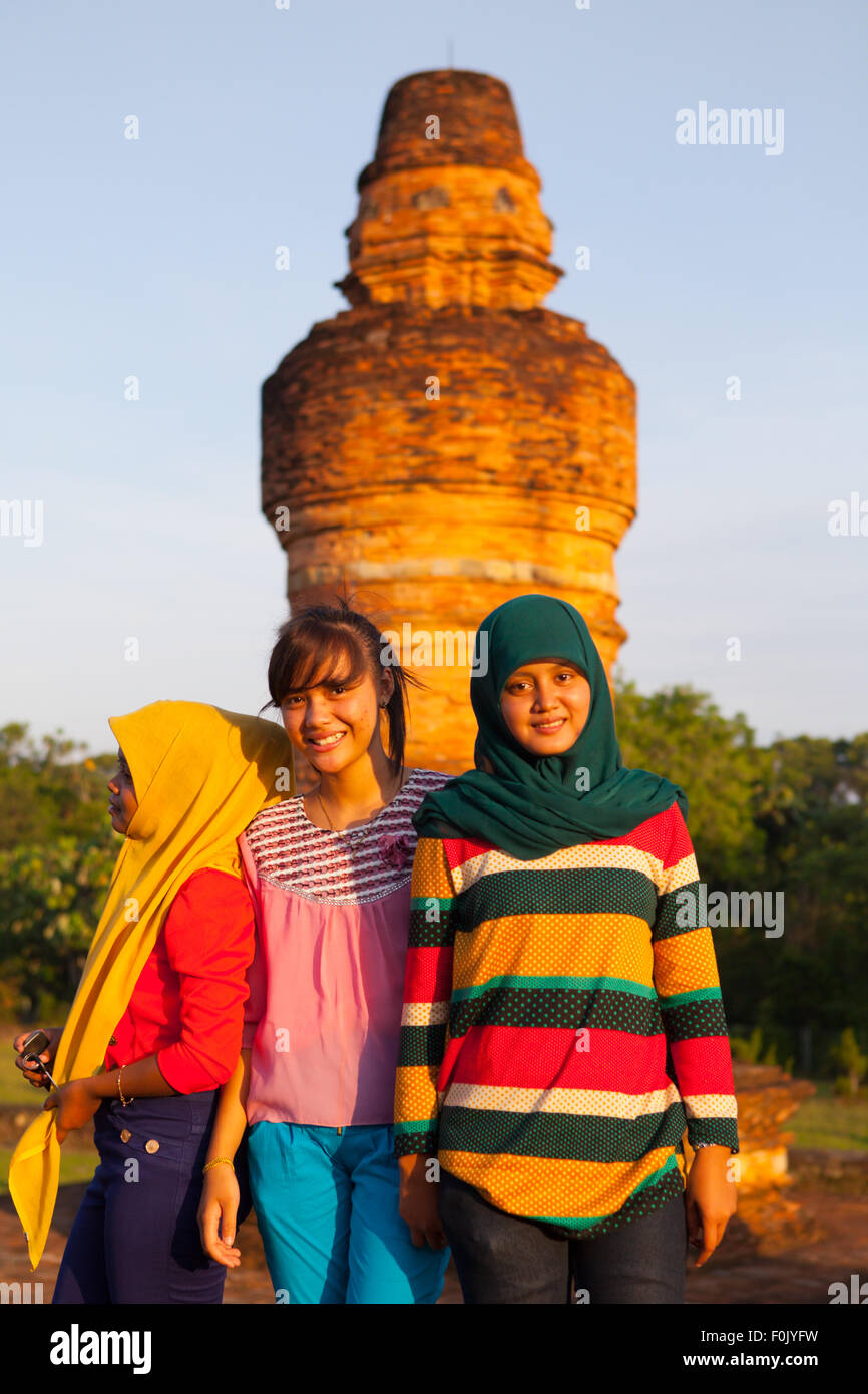 Le giovani donne stanno posando per una foto, in uno sfondo del Mahligai Stupa a Muara Takus complesso tempio a Kampar, Riau, Indonesia. Foto Stock