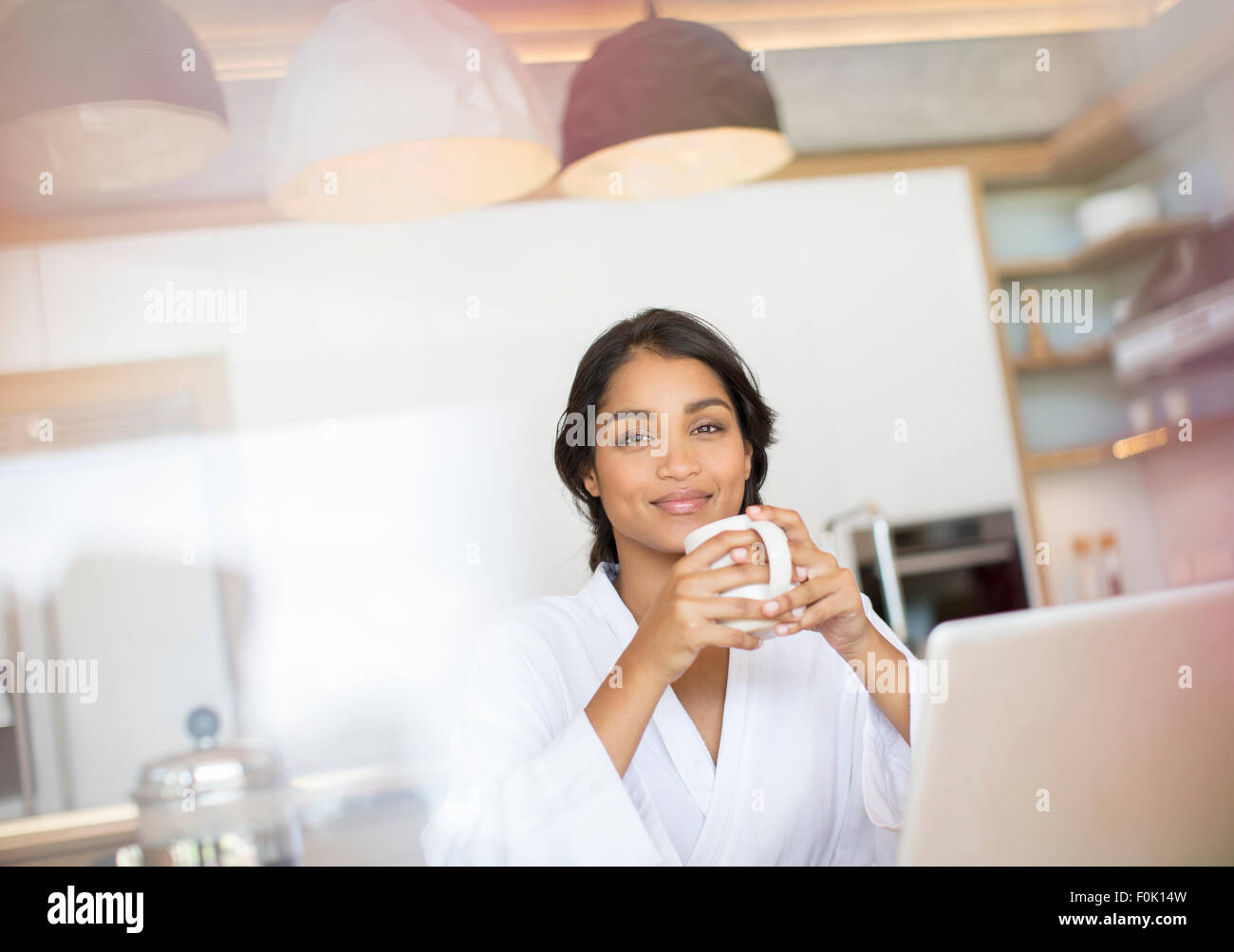 Ritratto di donna fiducioso in accappatoio di bere il caffè al laptop Foto Stock