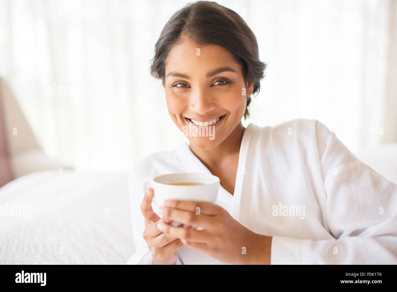 Ritratto di donna sorridente in accappatoio bere il tè Foto Stock