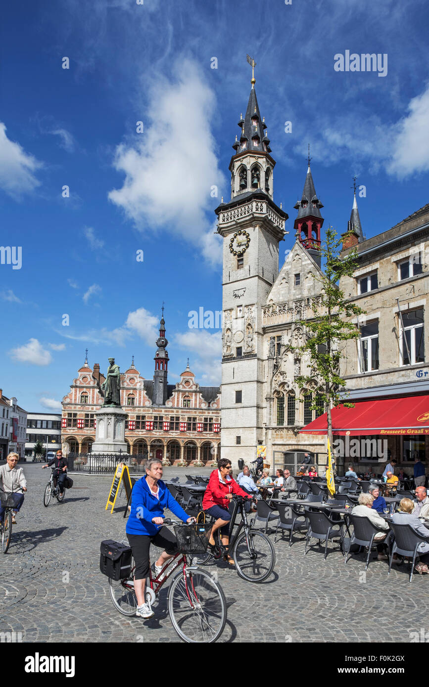 Belfry e anziani turisti in bicicletta passato caffetteria all'aperto nella piazza della città di Aalst / Alost, Fiandre Orientali, Belgio Foto Stock