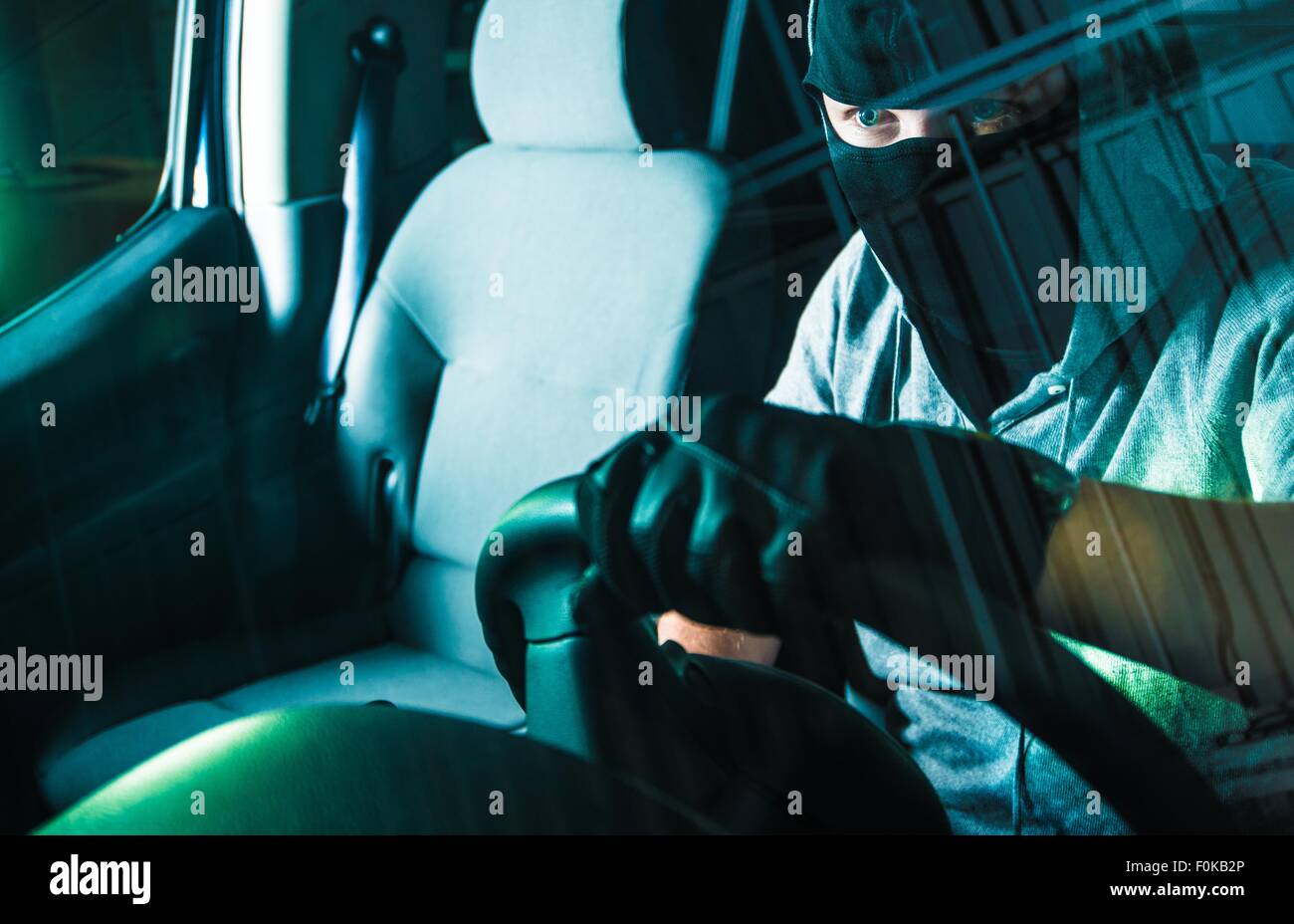 Il furto di auto in Carjacking. Giovani caucasici Carjacker maschio in maschera nera alla guida di auto rubate. Autoveicolo furto concetto fotografia. Foto Stock