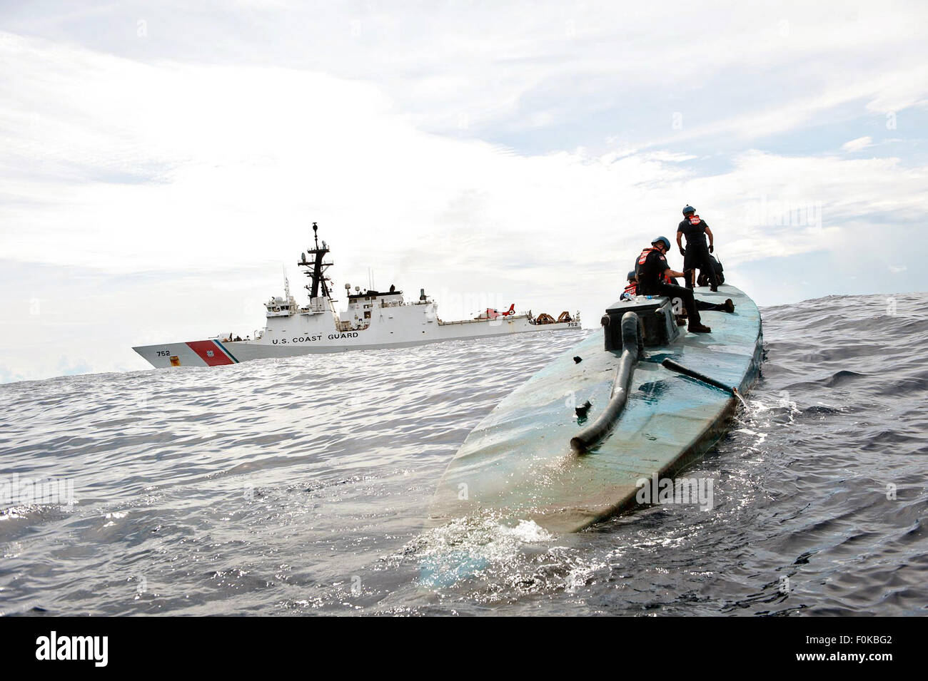 Un US Coast Guard team di imbarco dall'USCG taglierina Stratton indaga su un mezzo semovente a semi-sommergibile sommergibile per il trasporto di 6 tonnellate di cocaina interdetto in acque internazionali Luglio 19, 2015 al largo delle coste dell'America centrale. Foto Stock