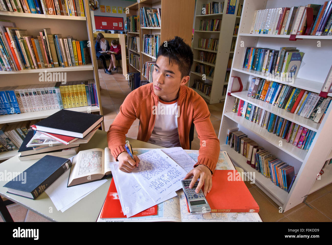 Coreano maschio adolescente studente pause nel pensiero profondo con il suo esame studi nella biblioteca della scuola Foto Stock