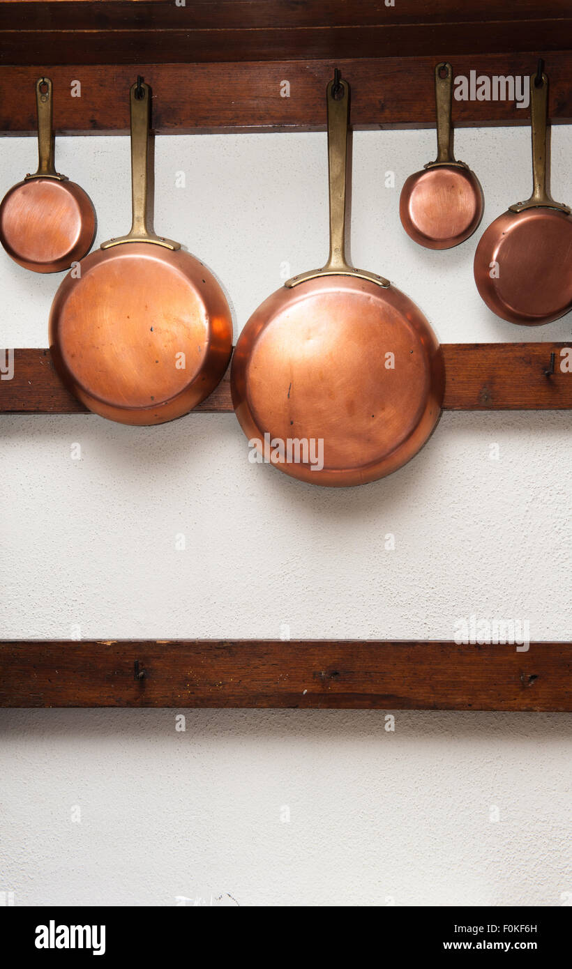 Fila di vintage pentole in rame, diverse dimensioni, appeso sul ripiano di legno in cucina, telaio verticale Foto Stock