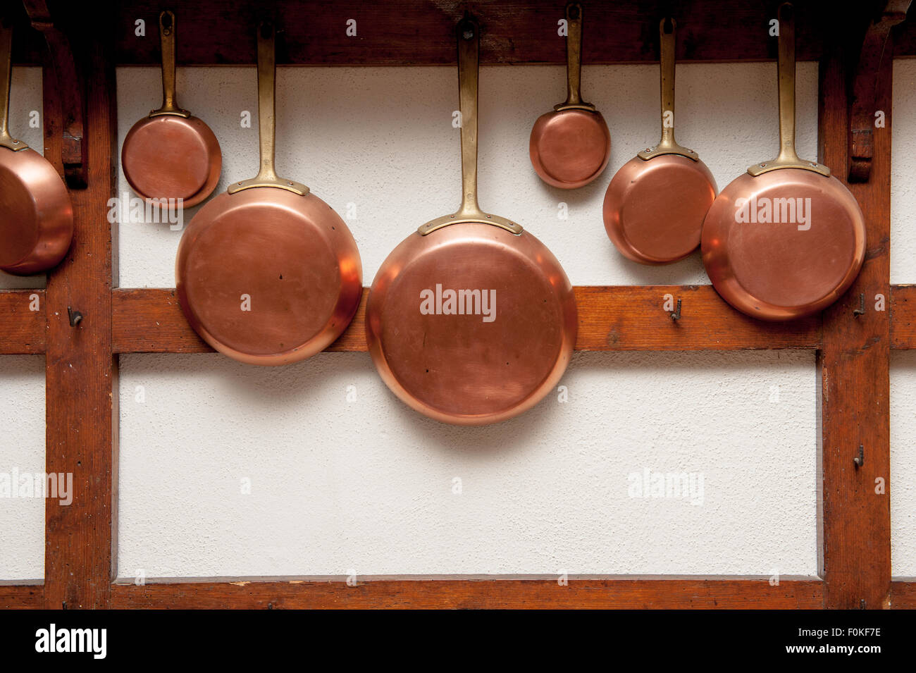 Fila di vintage pentole in rame, diverse dimensioni, appeso sul ripiano di legno in cucina, telaio verticale Foto Stock