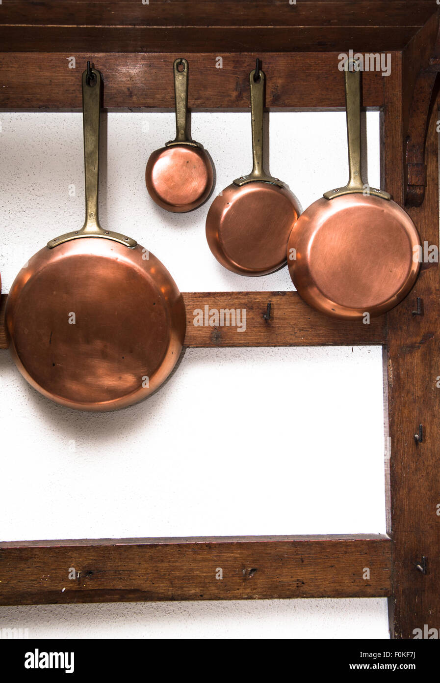 Gruppo di vintage pentole in rame, diverse dimensioni, appeso sul ripiano di legno in cucina, telaio verticale Foto Stock