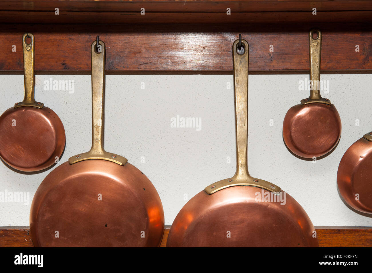 Fila di vintage pentole in rame, diverse dimensioni, appeso sul ripiano di legno in cucina, dettaglio Foto Stock