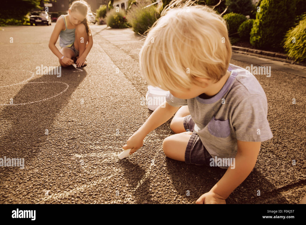 I bambini utilizzando il marciapiede chalk nel loro quartiere Foto Stock