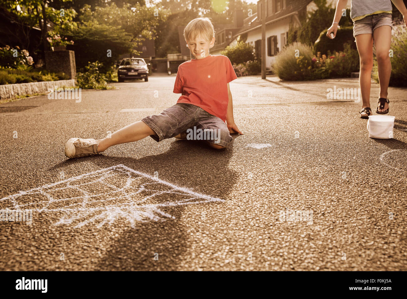 I bambini utilizzando il marciapiede chalk nel loro quartiere Foto Stock
