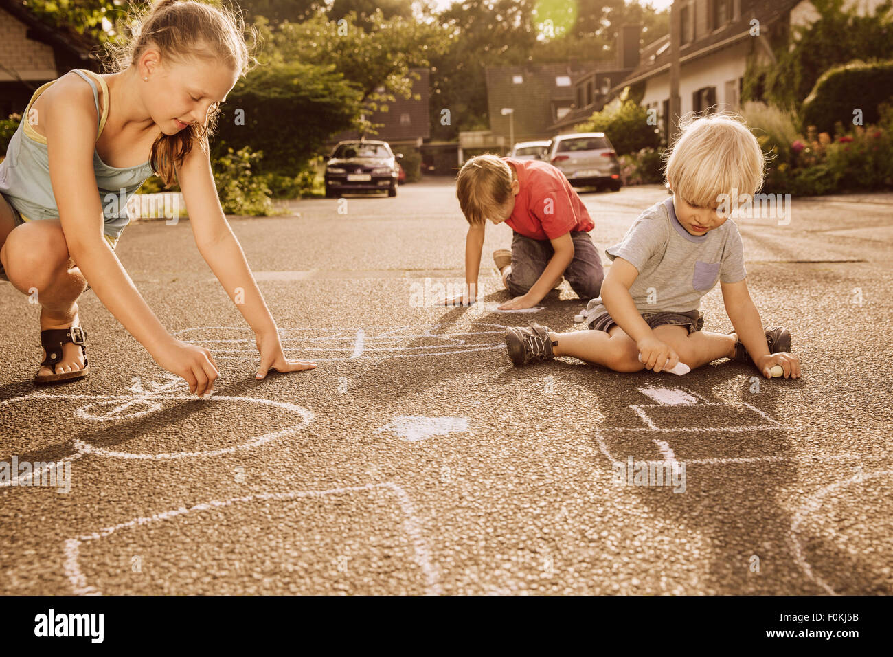 I bambini utilizzando il marciapiede chalk nel loro quartiere Foto Stock