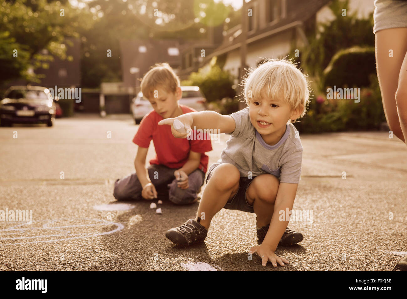 I bambini utilizzando il marciapiede chalk nel loro quartiere Foto Stock