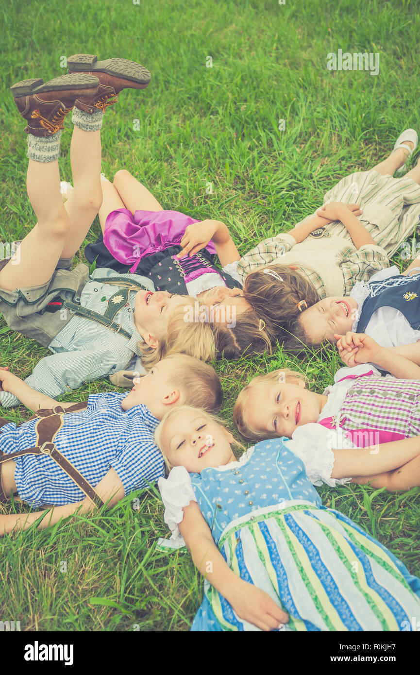 In Germania, in Sassonia, gruppo di bambini che indossano abiti tradizionali sdraiati su un prato in cerchio Foto Stock