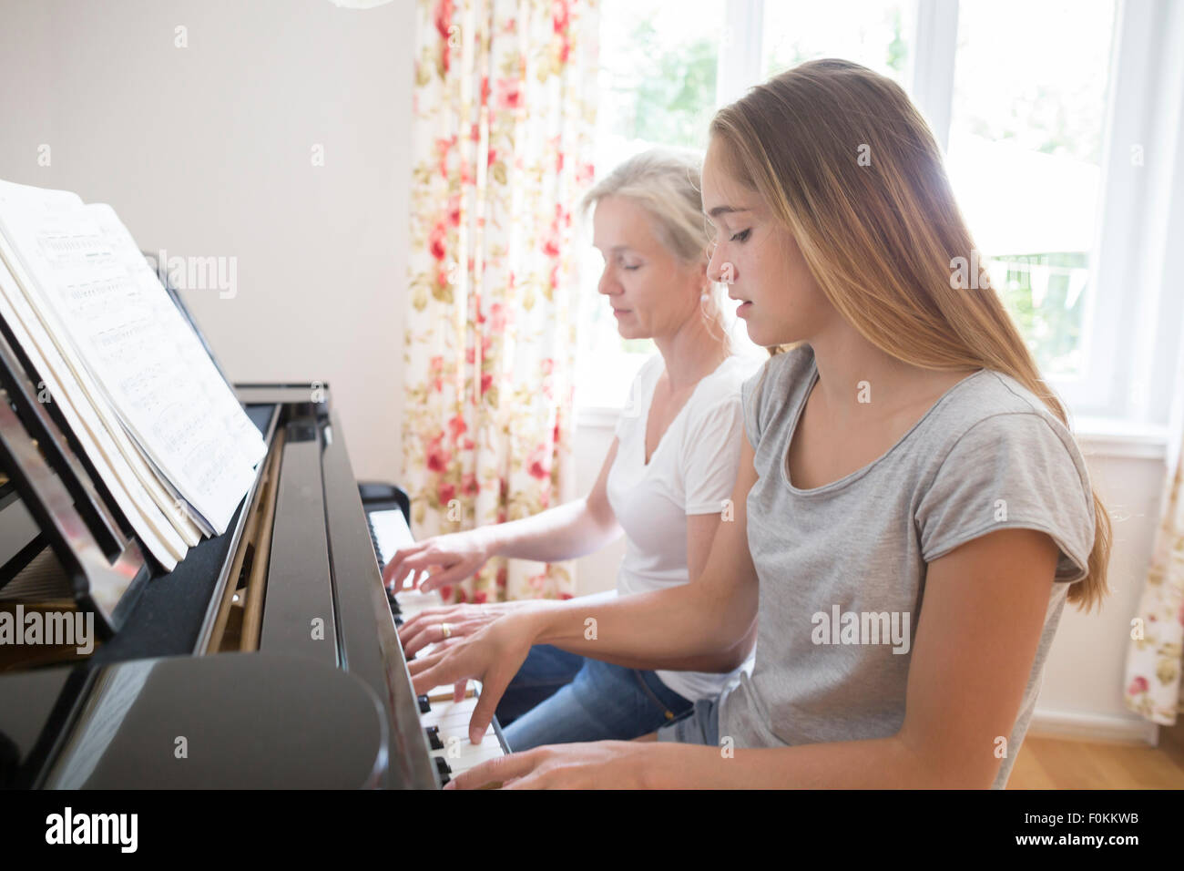 Madre e figlia suonando piano insieme Foto Stock