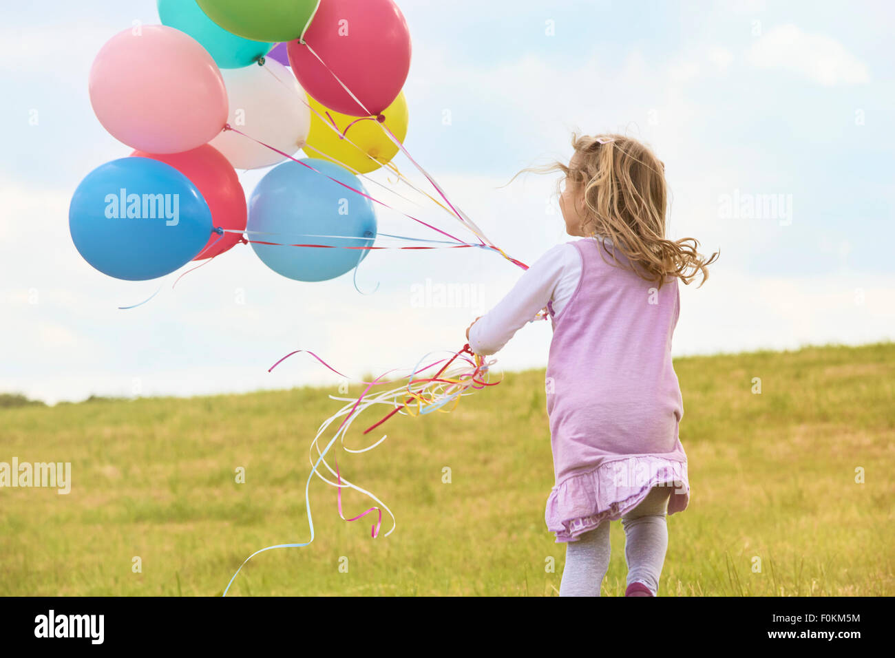 Bambina con palloncini in esecuzione su un prato Foto Stock