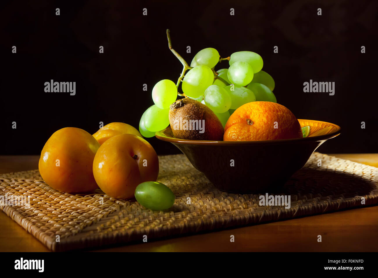 Ancora in vita. Il giallo di prugne, uva, arance e kiwi su un vassoio di vimini Foto Stock