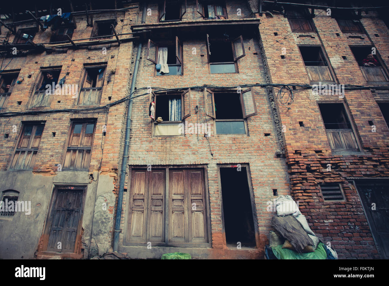 Un pessimo facciata nella vecchia città di Bhaktapur e alcune persone locali di guardare fuori, 24 aprile 2013. Foto Stock