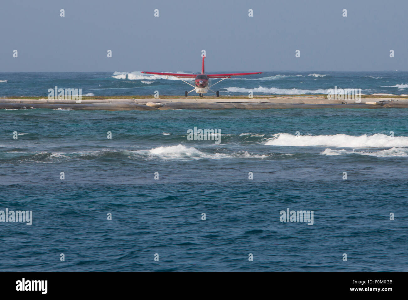 Piccolo rosso piano attorno al decollo su pista artificiale con l'oceano tutti intorno in isole San Blas, Panama 2014. Foto Stock