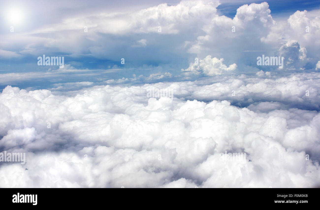 Le nuvole e il sole che splende alto nel cielo Foto Stock