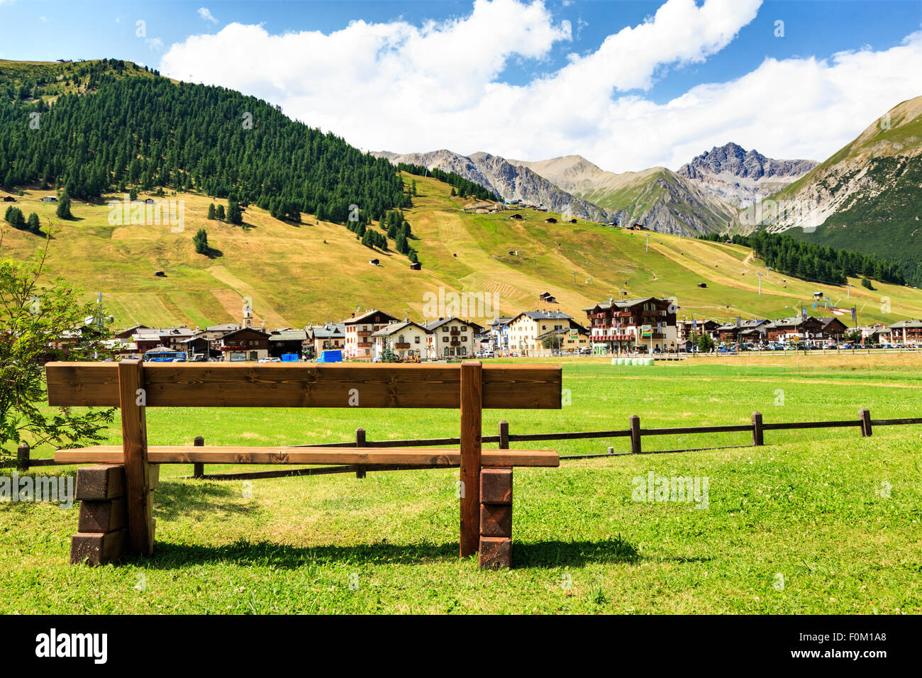 Rustico panca in legno con vista sui verdi campi di Livigno, Lombardia, Italia e le cime delle Alpi italiane in estate Foto Stock