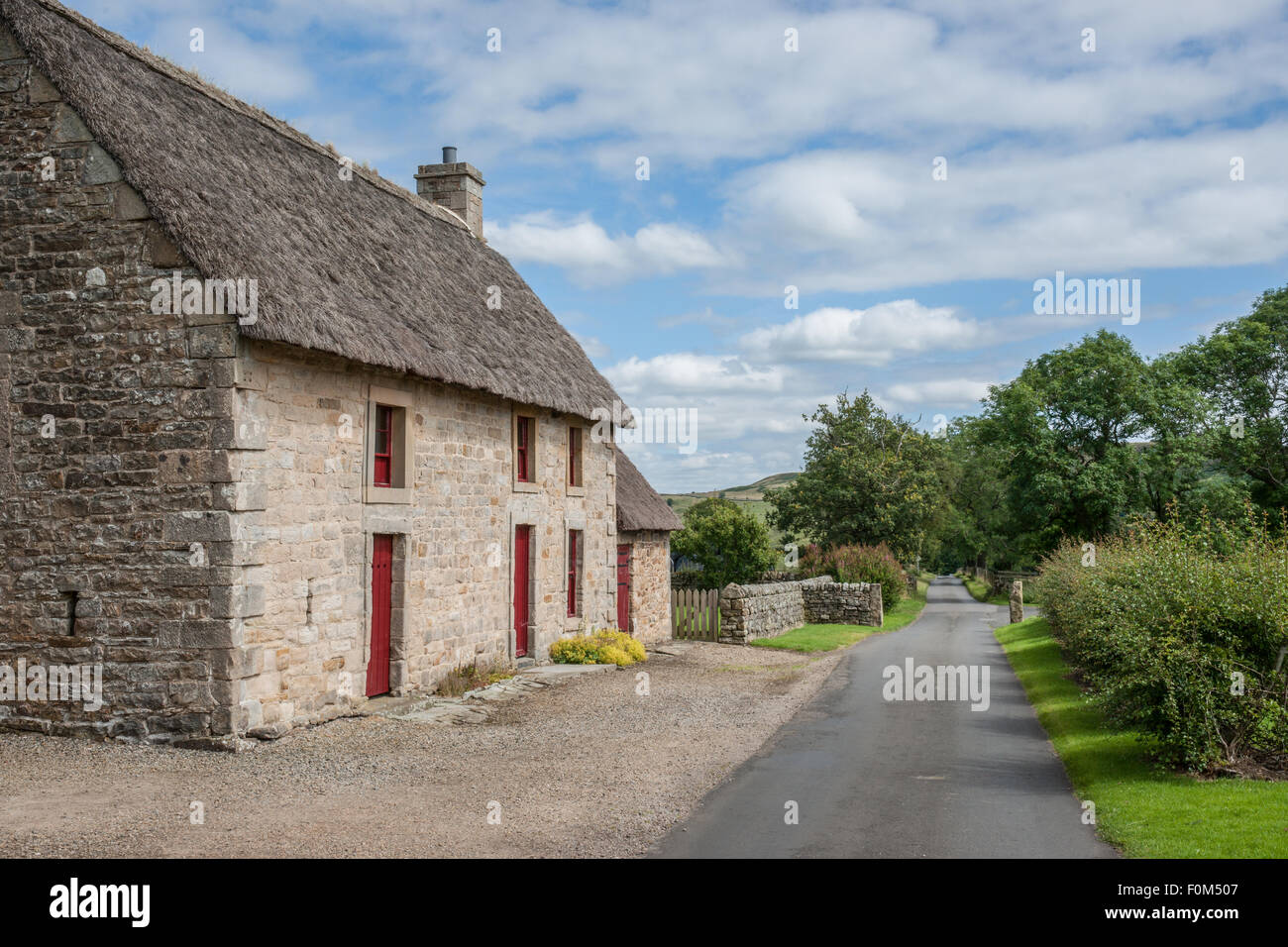 Un pittoresco inglese cottage in pietra con un tetto di paglia Foto Stock