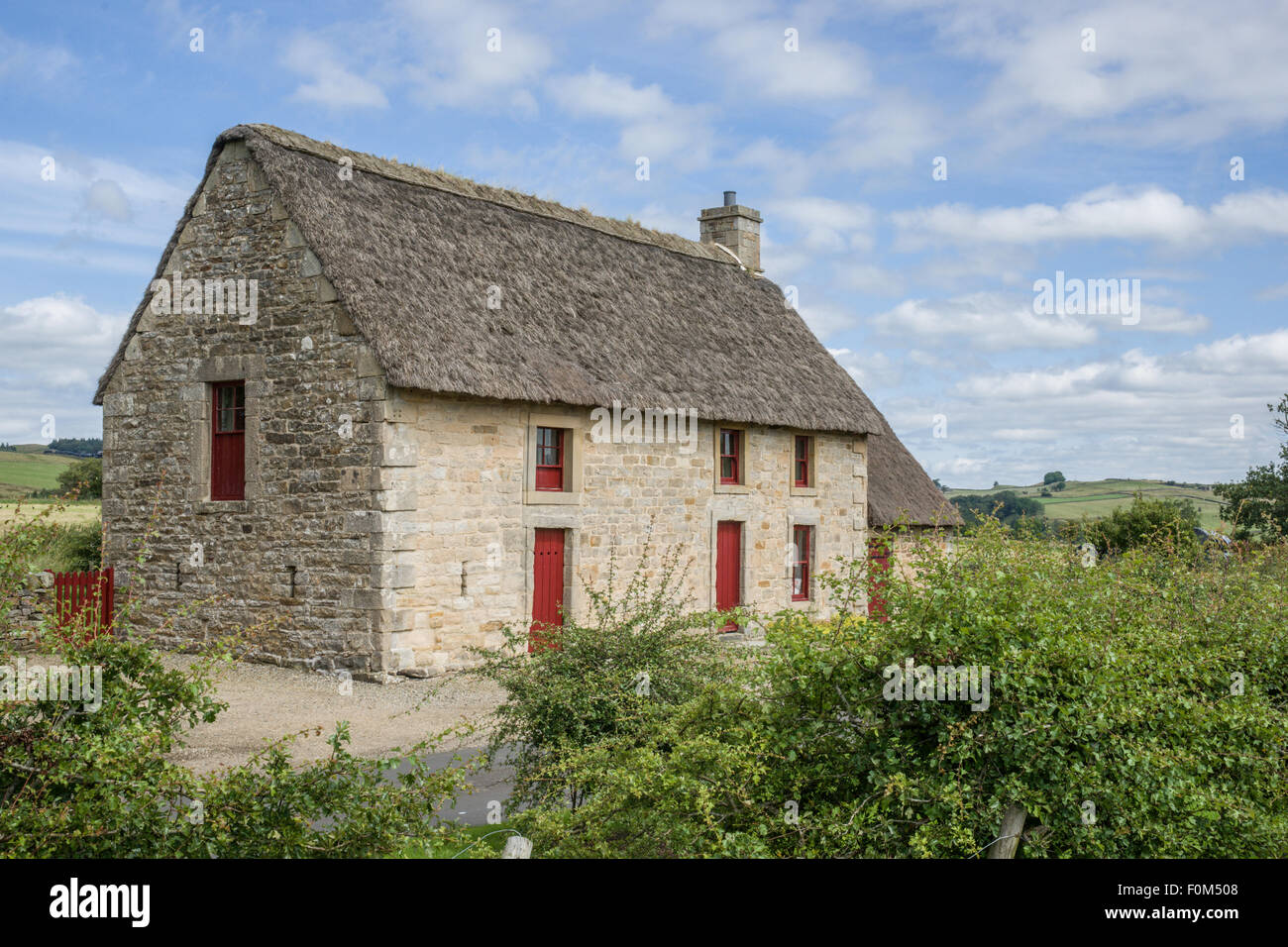 Un pittoresco inglese cottage in pietra con un tetto di paglia Foto Stock