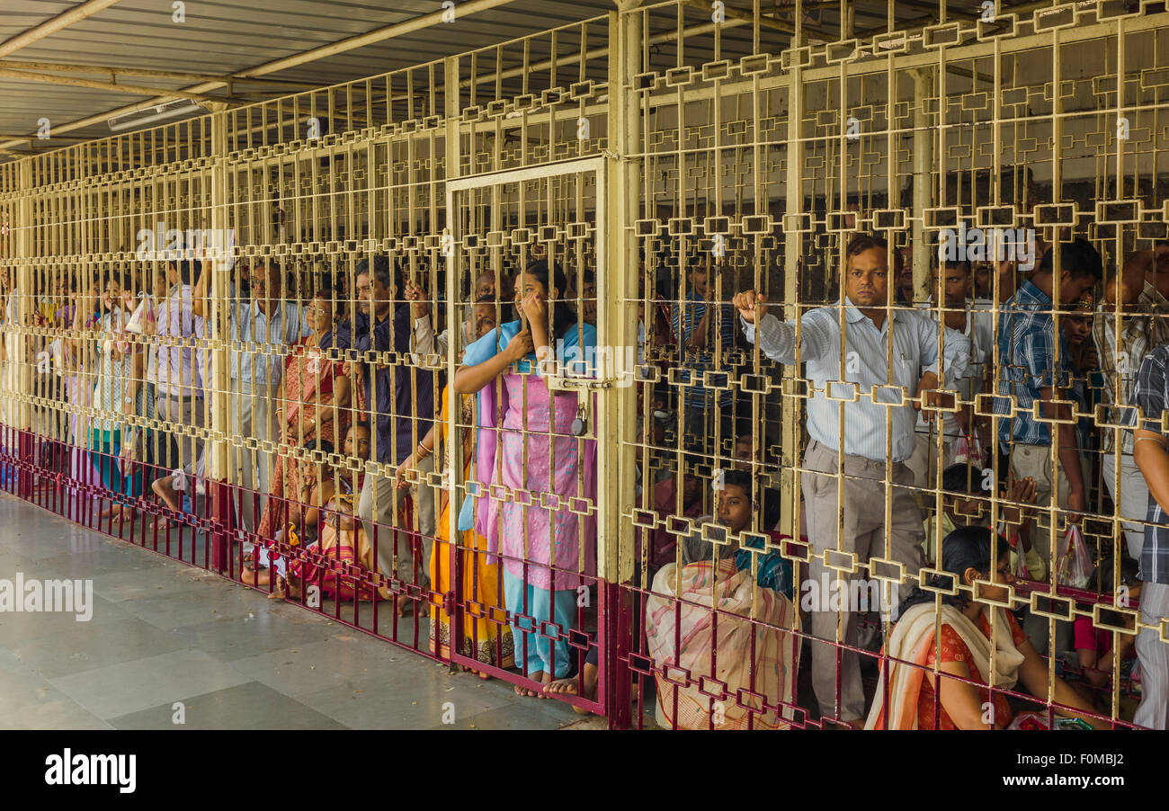 Pellegrini indù di attendere pazientemente in ferro le code in gabbia per la vista della divinità entro il tempio Kamakya, Assam, India. Foto Stock