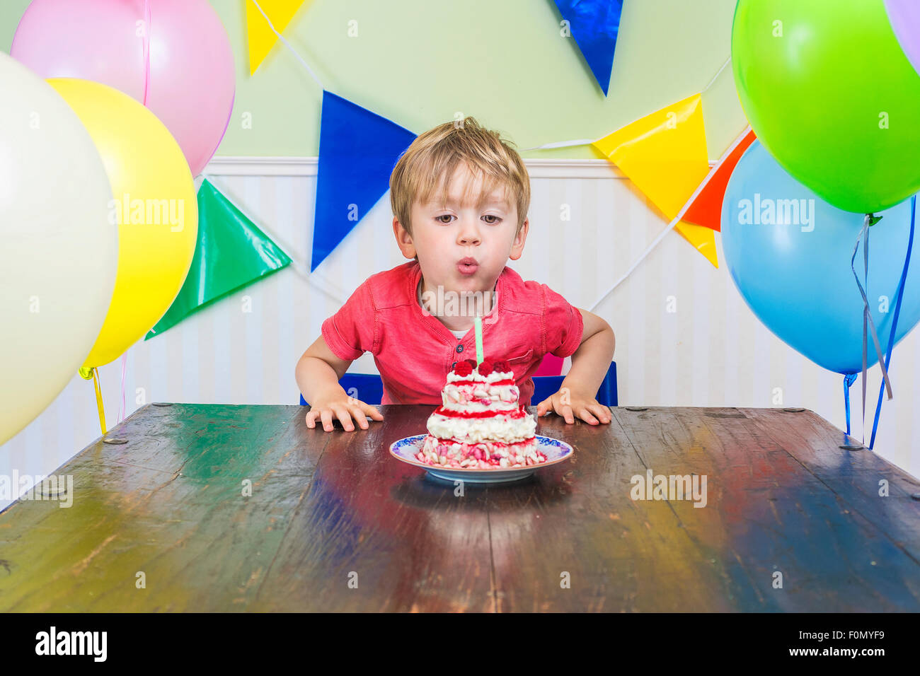 Carino kid soffiando fuori una candela di compleanno Foto Stock