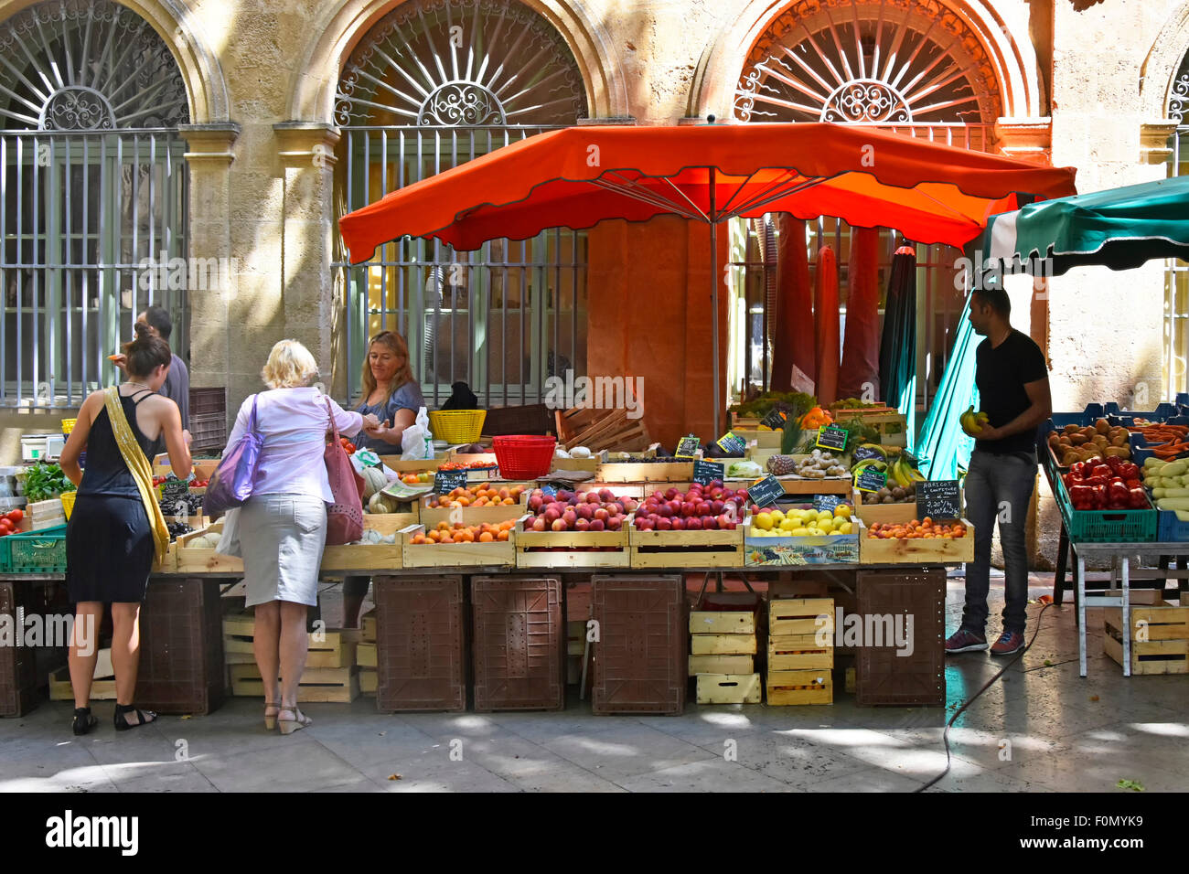 I clienti che acquistano prodotti di verdure a stallo sul mercato dal titolare di stallo nella frutta e nella verdura strada del mercato di Aix en Provence in Provenza nel sud della Francia Foto Stock
