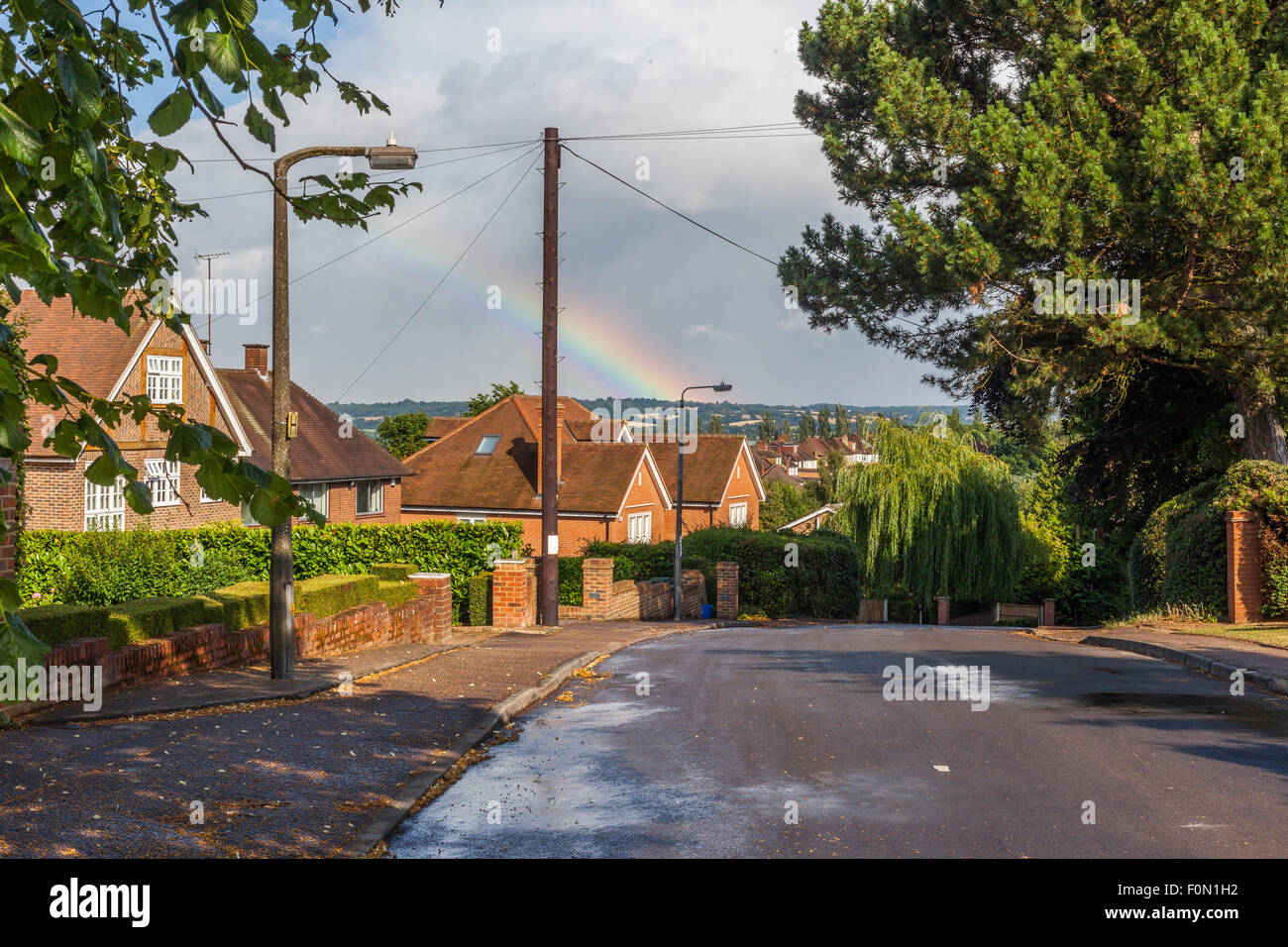 Scena di una zona residenziale dopo la pioggia, con arcobaleno sulla distanza lontana, Loughton, Essex. Inghilterra, Regno Unito. Foto Stock