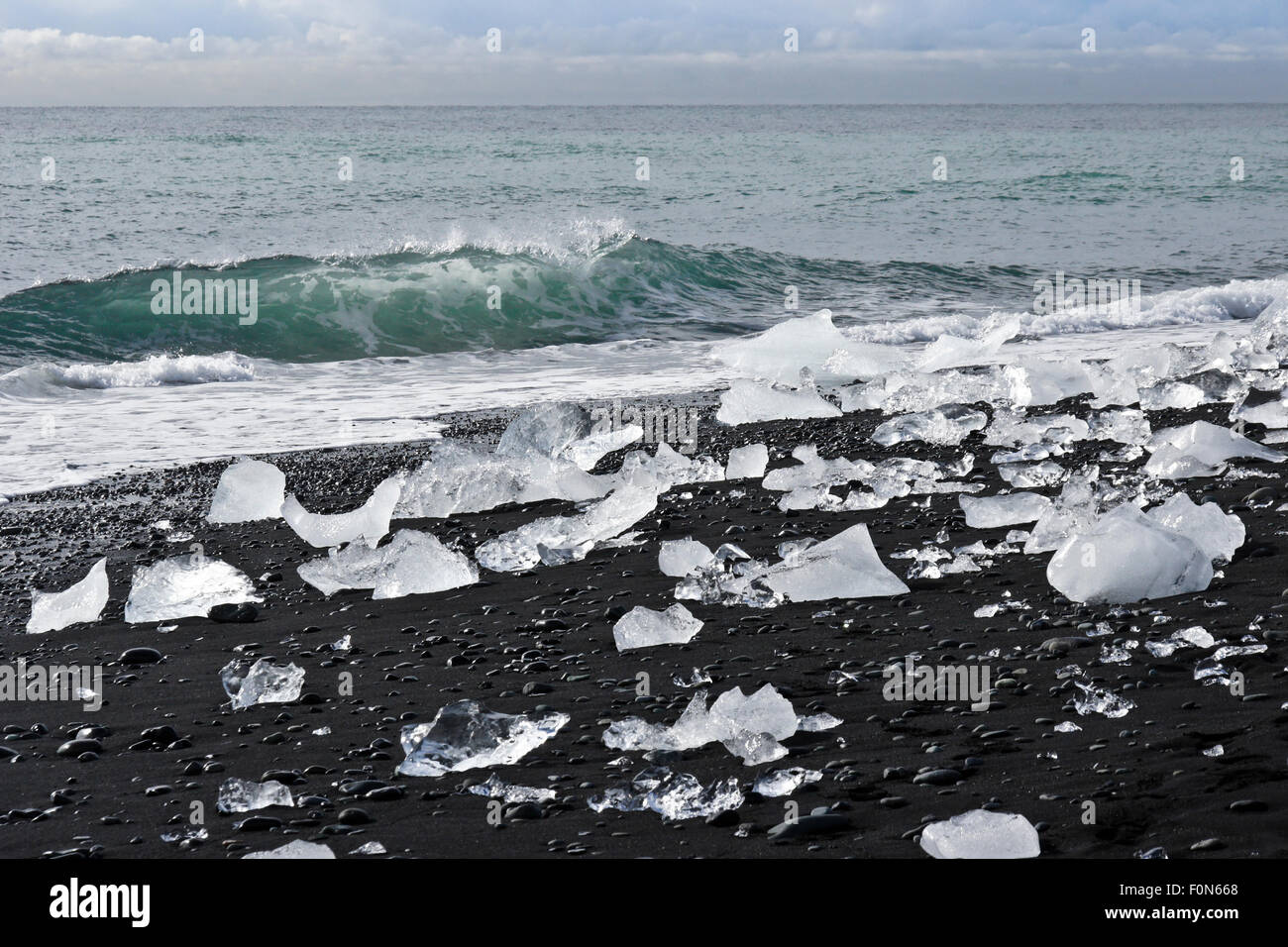 Il ghiaccio del ghiacciaio lavato fino sulla spiaggia di sabbia nera a Jokulsarlon, sud dell'Islanda Foto Stock